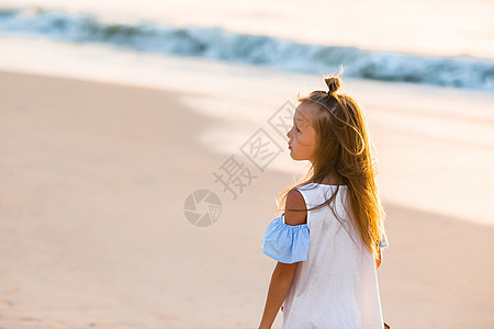暑假期间海滩上可爱的小女孩在沙滩上海岸线女性跳跃幸福天空热带女孩乐趣情感异国图片