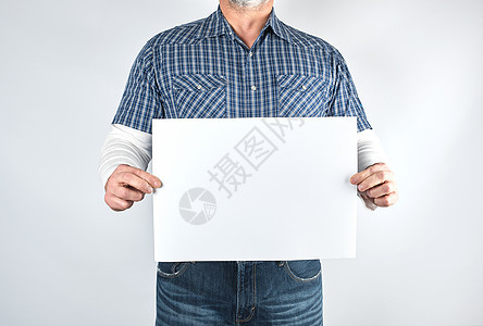 一件蓝色格子花呢衬衫和牛仔裤的人拿着一个空白的长方形男人小样海报手指矩形工作室身体成人床单商业图片