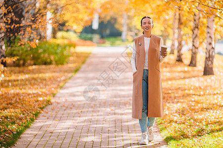 秋瀑概念  美丽的女人在秋公园喝咖啡 在秋天的树叶下女士季节公园女性饮料女孩快乐杯子拿铁叶子图片