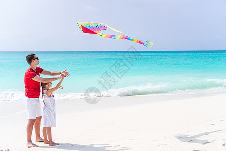 家庭在热带白沙滩一起放风筝风筝父亲飞行男人童年喜悦假期爸爸天空女孩图片