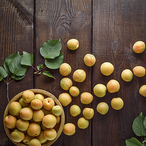 分散在棕色木制桌上的成熟杏子圆形饮食黄色叶子木头水果盘子食物桌子营养图片