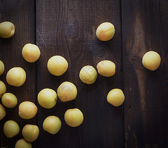 棕色木制桌子上分散的成熟黄杏子图片