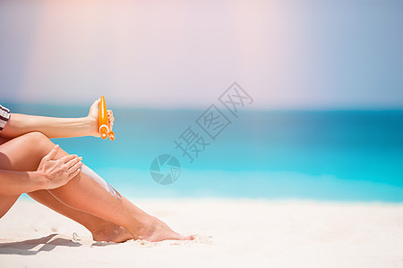 女孩用手擦晒黑玻璃瓶子 背景是松绿水系数奶油身体生活防晒阳光日光浴洗剂海滩假期图片