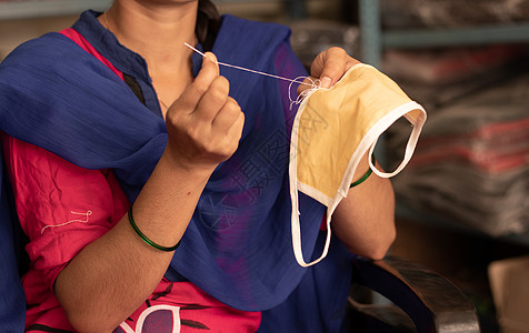 女孩在家里手工编织 DIY 面罩 以防止印度发生 covid-19 或冠状病毒大流行——由于印度制造口罩的妇女缺少医用口罩图片