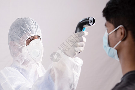流行病学家在医院柜台用数字温度计检查发烧以进行扫描并防止冠状病毒或 COVID-19 爆发 进入大楼或诊所前的人员筛查点图片