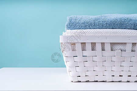 蓝色背景的白色洗衣篮里一堆干净毛巾棉布塑料工作室洗澡桌子家务篮子织物浴室纺织品图片