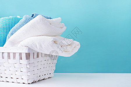 蓝色背景的白色洗衣篮里一堆干净毛巾洗澡家庭浴室织物篮子洗涤衣服棉布塑料卫生图片