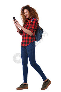 全身年轻女子 用手机和手提袋在孤立的白色背景上行走图片