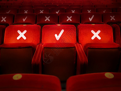 3个红色天鹅绒空臂椅在音乐厅内被照亮图片