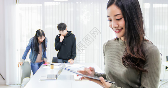 亚洲女学生使用数字平板电脑在线查找工作和学习信息图片