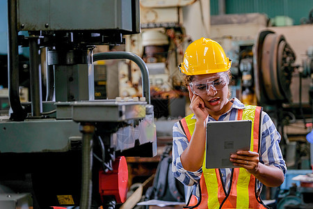 技术员妇女用平板电脑检查或维修工厂中的机器图片