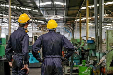 两个技术员的背部 模糊的画面 两个技师站着看各种机器 在工厂里图片