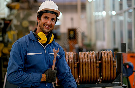 工人或技术技工的肖像 男人握着扳手 微笑 站在工厂铜管前图片