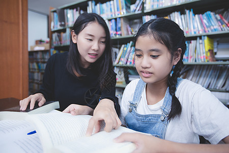 两名亚洲女学生在图书馆读书和使用笔记本 他们都是亚裔图片