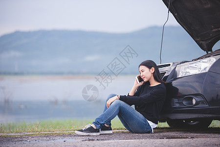 亚裔妇女正在使用电话给汽车修理工打电话维修街道服务运输情况帮助兜帽女孩检查司机图片