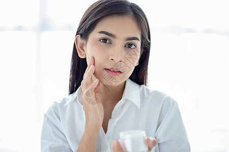 一个美丽的亚洲女性 使用皮肤护理产品 湿润剂投标美甲手指保湿女士温泉卫生职业治疗眼睛图片