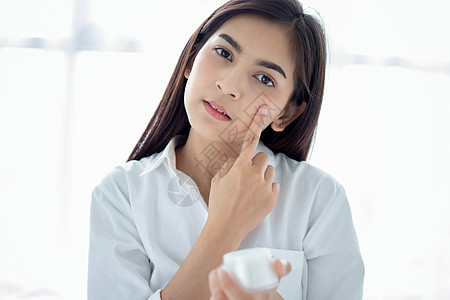一个美丽的亚洲女性 使用皮肤护理产品 湿润剂身体职业胶原洗发水制药化妆品滴管女士眼睛润肤图片