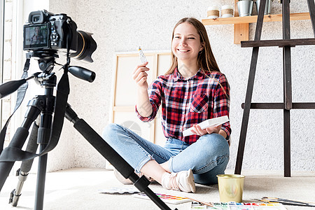 一位女士使用安装在三脚架上的数码相机为她的艺术博客制作视频技术教育爱好互联网水彩艺术家播送记录训练工艺图片