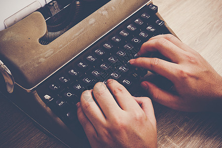 手打在老牌打字机上 在木制桌上桌子工作古董作者作家黑色键盘机器办公室编辑图片