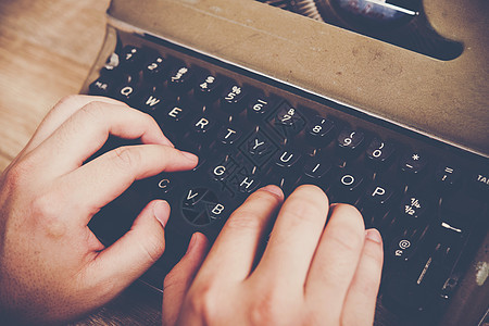 手打在老牌打字机上 在木制桌上键盘作家编辑办公室机器古董桌子记者黑色工作图片