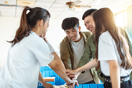 将双手放在彼此的顶峰上的学生们图片