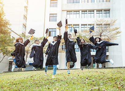 快乐学生在大学校园庆祝和跳跃毕业礼服中欢乐的学生仪式团体朋友乐趣证书学士庆典长袍女士成就图片