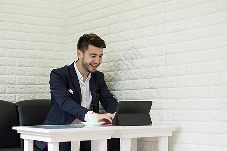成功的青年商务人士在办公室用笔记本电脑工作设计师项目咖啡写作男性商业潮人桌子套装互联网肖像高清图片素材