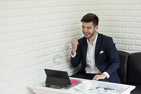 成功的青年商务人士在办公室用笔记本电脑工作咖啡商业经理写作男人白色套装项目相机思维现代的高清图片素材