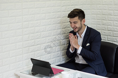 成功的青年商务人士在办公室用笔记本电脑工作互联网潮人桌子经理商业相机男人套装白色写作使用高清图片素材