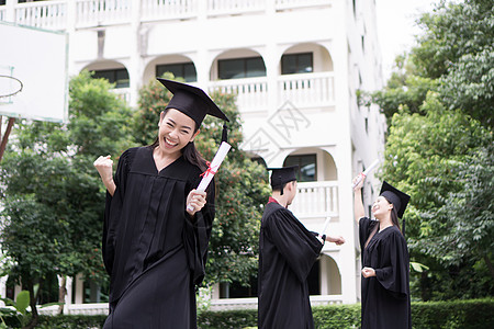 与朋友在后的朋友站在一起的快乐学生获得毕业文凭微笑教育成就团体国际砂浆学校庆典学士大学图片