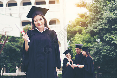 与朋友在后的朋友站在一起的快乐学生获得毕业文凭微笑学士国际大学教育成就团体砂浆庆典学校图片