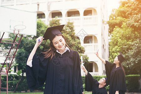 与朋友在后的朋友站在一起的快乐学生获得毕业文凭国际学士砂浆微笑大学团体教育成就庆典学校图片