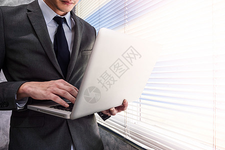 站在办公室的窗户上时使用笔记本电脑近距离接近商务人士图片