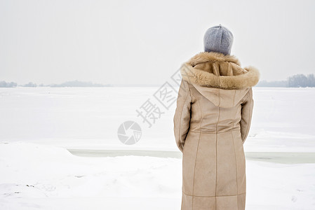 女人靠近冬季的冷冻河薄片中年头发外套女士女性兜帽沉思女孩成人图片