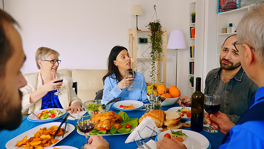 年轻的天主教女青年及其母亲饮葡萄酒食物祖父喜悦快乐微笑男人享受眼镜朋友们桌子图片