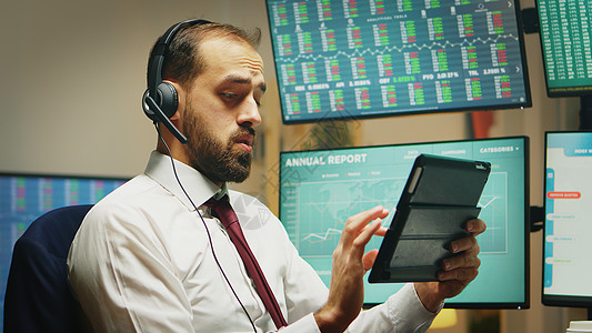 从总部办公室抽查数码平板电脑数据的股票交易员工作金融金融危机经济商务家庭背景监视数字风险胡子耳机图片