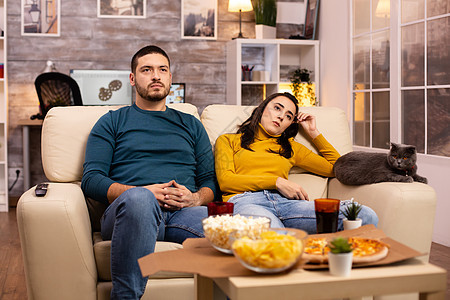 情侣在看电视时为他们最爱的团队欢呼爆米花午餐女性女朋友食物男人苏打成人情绪公寓图片