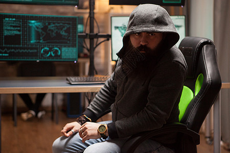 穿着连帽帽衫的危险的留胡子黑客男性技术选举房间兜帽编程电脑钓鱼刑事互联网图片