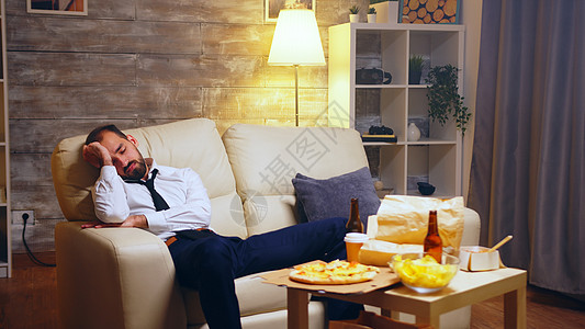 在沙发上睡着的 工作繁重的商务人士人士盒子睡眠食物电视程序客厅垃圾电影公寓图片