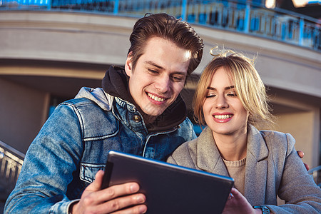 快乐的情侣或朋友在街上拥抱并分享一块平板电脑朋友们城市女士乐趣想像力夫妻假期男人学生街道图片