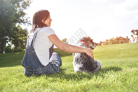 在阳光明媚的日子里 漂亮的成年白人快乐女人和她心爱的狗在公园里休息 快乐的白人女人拥抱她心爱的狗 爱动物概念图片