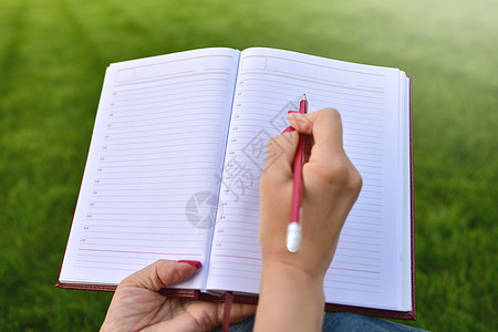 在公园笔记本上 在教育和知识中的概念上写作的青年妇女青少年微笑文档日记思考诗歌学生笔记铅笔女性图片