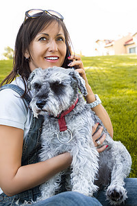 一个快乐的女人的肖像 她拥抱她深爱的Schnauser狗 和在电话旁说话图片