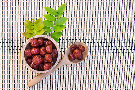 糖浆中的鹅莓放在木碗和竹棍上的勺子里图片