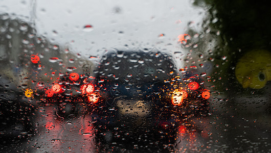 雨滴在挡风玻璃上 背景的夜晚城市灯光模糊不清窗户液体蓝色大灯旅行天空交通风暴反射下雨图片