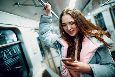 年轻女子在地铁里带着手机微笑 在地铁概念上无一例外图片