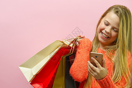 女孩手拿着现代手机进行网上购物 屏幕上的白色屏幕 与智能手机的网上购物概念 粉红色背景的女孩图片