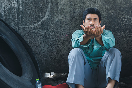 一个坐在墙边的男人城市危机陶醉流浪汉睡眠乞丐帮助男性街道寂寞图片