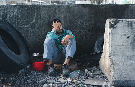 悲惨地坐在墙边的无家可归的人贫困陶醉孤独乞丐压力男人城市街道危机司机图片