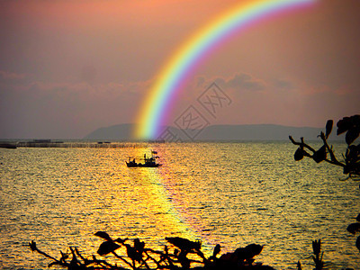 海中模糊的帆船日落彩虹 天空在水上反射彩虹图片